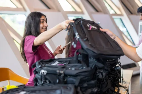 An event host hands over a KI backpack.