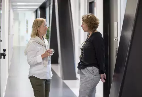 Two women talking in a corridor.