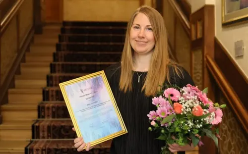 Portrait of PhD Student with Diploma and flower boquet