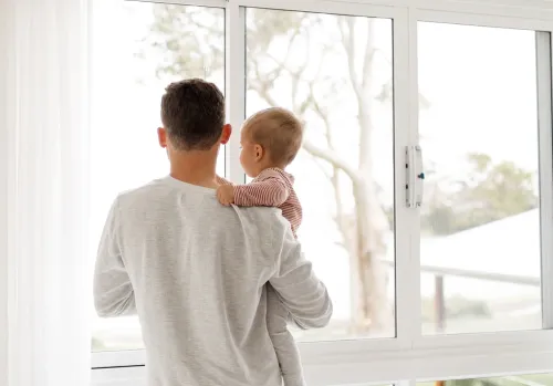 Father holding child looking out a window