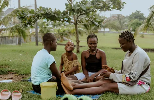 Group of people sitting in the grass and playing card