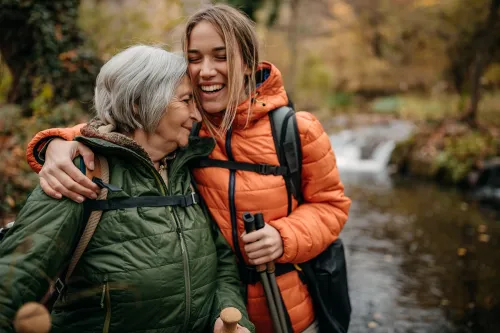 Senior women and her granddaughter hiking, walking through forest