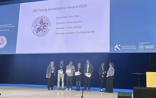 Seven people standing on a stage. Four of them are holding diplomas.
