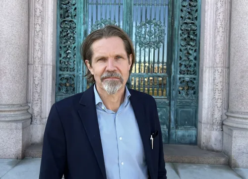 Photo of a man infront of large doors.