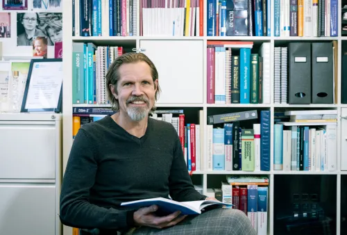 Smiling man infront of a book case.