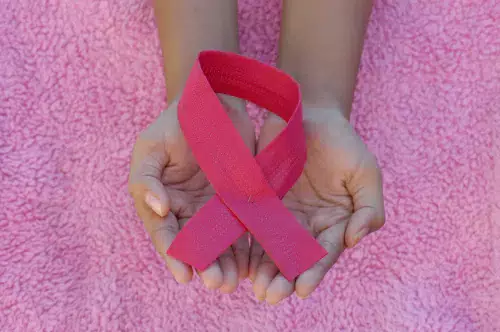Hands holding a pink ribbon.