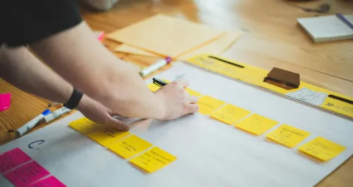 Person writing at sticky notes.