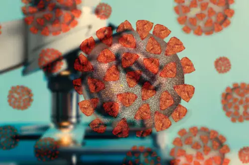 The image shows illustrated and colourful coronavirus with a microscope in the background.