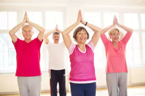 Grupp av äldre människor som alla gör samma yogarörelse.